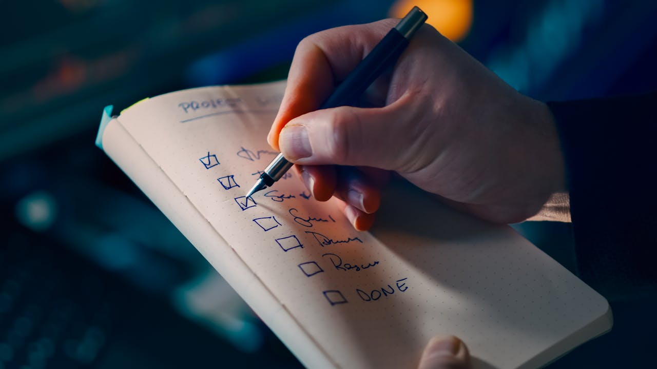services-03 Close-up of a hand writing a checklist in a notebook, symbolizing productivity and organization.